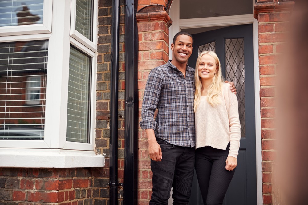 portrait of proud young couple standing outside first home together