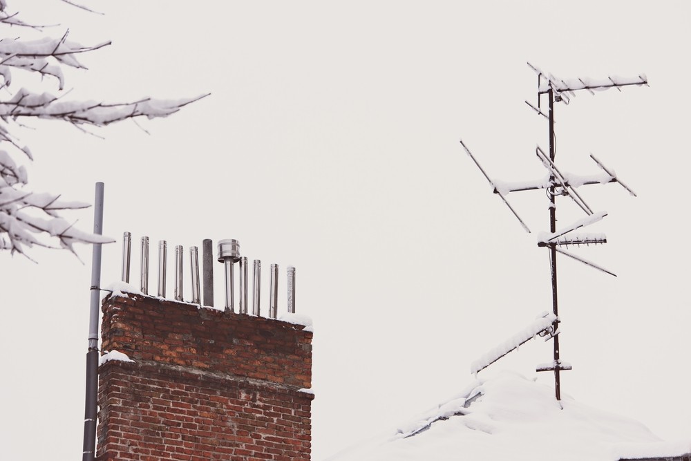 the tv antenna is covered with snow on the roof.